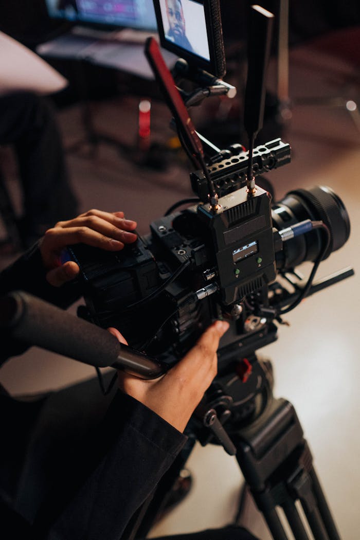 Close-up of a person operating a professional video camera on a tripod, focusing on filmmaking.